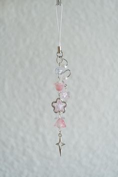 a silver charm with pink and white beads hanging from it's side on a string