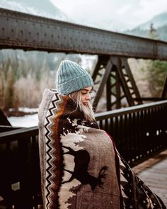 a woman standing on a bridge wearing a shawl