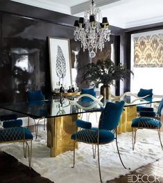 an elegant dining room with blue velvet chairs and gold table, chandelier in the background