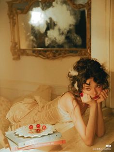 a woman laying on top of a bed in front of a cake with cherries