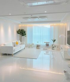 a living room with white furniture and curtains on the windowsills is lit by recessed lights