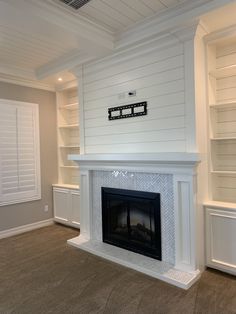 an empty room with a white fireplace and shelves on either side of the fire place