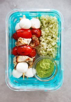 a plastic container filled with meat and veggies on skewered skewers