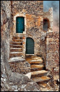 an old stone building with stairs leading up to the door and window on top of it