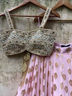 A three-piece powder pink butti mirror lehenga set from the Priti Sahni collection. This elegant powder pink butti georgette lehenga with big ruffle detailing and gota border is paired with our classic pearl work and mirror bustier. The lehenga has side hanging ball tassels to the waistline. And the blouse has a mirror-sequins tassel tie-up at the back. The outfit is completed with a powder pink net sequined butti work dupatta with scalloped edging. Pink Gota Work Choli For Reception, Pink Sequined Georgette Sets, Embellished Pink Sets For Navratri, Pink Choli With Mirror Work For Navratri, Pink Sequined Anarkali Set For Navratri, Pink Mirror Work Sharara For Reception, Pink Sharara With Mirror Work For Reception, Navratri Pink Choli With Mirror Work, Pink Sequined Choli For Navratri