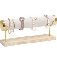 a white napkin holder with gold rings and bracelets on it's end, sitting on top of a wooden stand