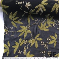 the fabric is black with gold flowers and leaves on it, along with other material