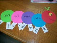 four paper circles with words on them sitting on top of a wooden table next to an apple