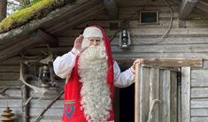 a man dressed as santa claus waves to the crowd from his small cabin on stilts