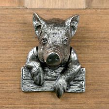 a metal pig figurine sitting on top of a wooden doorknott