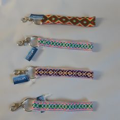 three lanyards with key chains attached to them on a white surface, one has a name tag and the other has a logo