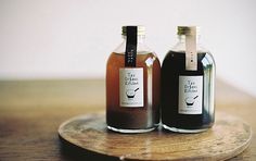 two bottles of liquid sitting on top of a wooden plate