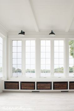 an empty room with large windows and wicker storage baskets on the floor in front of them