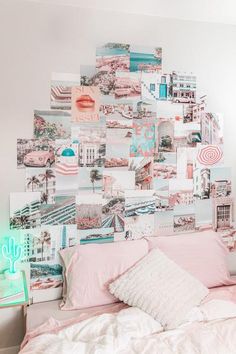 a white bed topped with lots of pink and blue pictures next to a green neon light