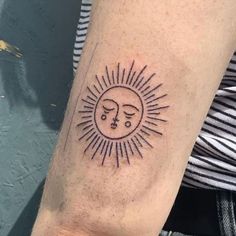 a person with a sun and moon tattoo on their arm that has two faces in the middle