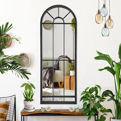 a mirror sitting on top of a wall next to potted plants