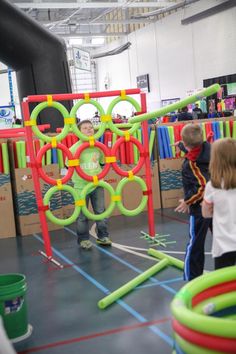 two children playing in an indoor play area with toys and water hoses on the floor