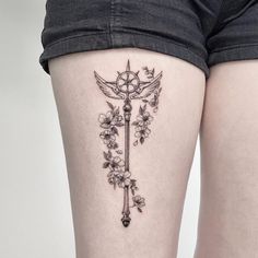 a woman's thigh with flowers and an old style key tattoo on the side