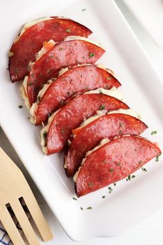 slices of salami on a white plate with wooden utensils