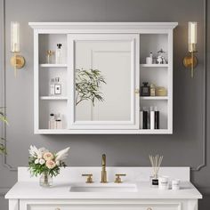 a bathroom vanity with white cabinets and gold fixtures on the mirror above it is a potted plant