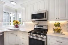 a kitchen with white cabinets and stainless steel appliances