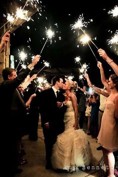 a bride and groom are surrounded by sparklers