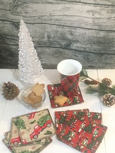 christmas themed place mats and napkins on a white table with pine cones, fir trees, and a red truck