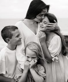 a woman is hugging two children and they are both holding her hands over their face