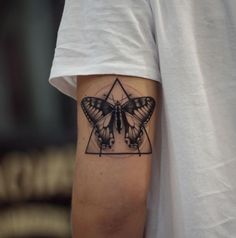 a black and white photo of a butterfly tattoo on the left upper half of the arm