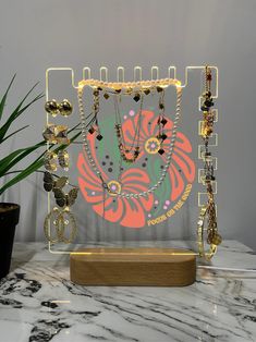 a display case with jewelry on it and a potted plant in the back ground