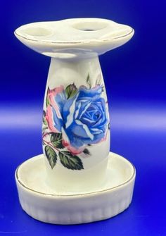 two white candlesticks with blue and pink roses on them