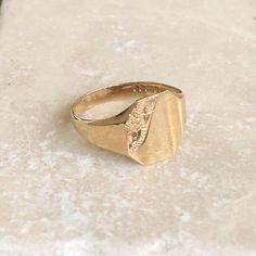 A vintage 9 carat gold signet ring with a engraved detailing in the corner. This charming piece has a great shape and a small amount of detailing on the corner of the face.CONDITION: Wear consistent with age and use. Please see photos for more detail.ASSAYED IN BIRMINGHAM, MADE CIRCA.1987APPROX. BAND WIDTH (SMALLEST): 2.5mmAPPROX. FACE SIZE: 12mm x 11mmRING SIZE: UK: R | US: 8 1/2WEIGHT: 2.1g Vintage Tarnish Resistant Signet Ring For Weddings, Vintage Wedding Signet Ring Tarnish Resistant, Vintage Tarnish-resistant Signet Ring For Wedding, Vintage Tarnish-resistant Signet Ring For Promise, Vintage Gold Engraved Ring Tarnish Resistant, Vintage Tarnish Resistant Signet Ring For Promise, Vintage Tarnish Resistant Initial Ring For Anniversary, Vintage Engraved Ring For Anniversary, Gold Antique Signet Ring For Promise