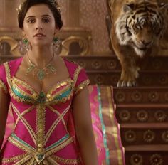 a woman in a pink dress standing next to a tiger