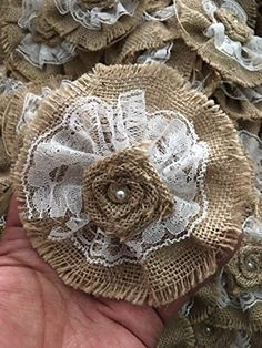 a hand holding a piece of burlocked fabric with lace flowers on it