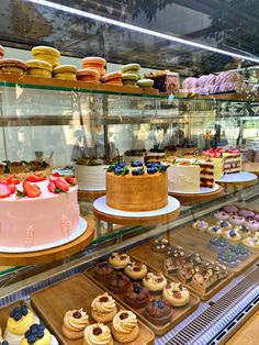 a display case filled with lots of different types of cakes and pastries on top of wooden trays