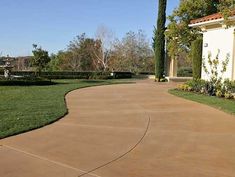 a driveway with grass and trees in the background