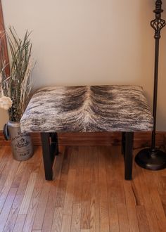 a wooden bench sitting on top of a hard wood floor next to a vase filled with flowers