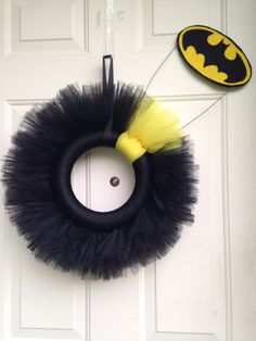 a door hanger with a black and yellow batman wreath hanging from it's side