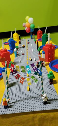 a lego table is set up for a birthday party with balloons and streamers on it