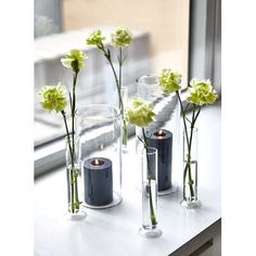 three vases with flowers in them sitting on a window sill