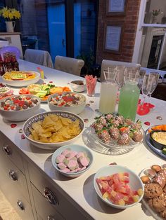 a table filled with plates and bowls of food next to a tall glass vase full of drinks