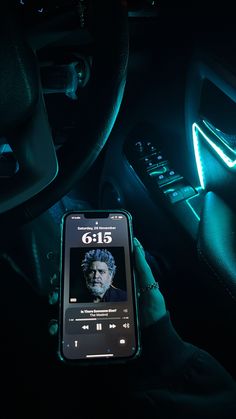 a cell phone sitting in the center console of a car, with an image of george monroe on it