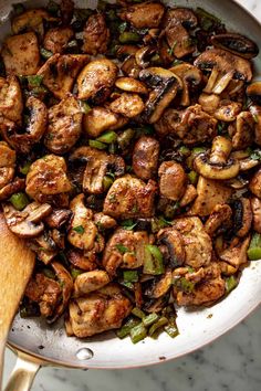 a skillet filled with chicken, mushrooms and green peppers on top of a marble counter