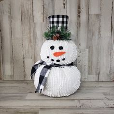 a snowman made out of toilet paper sitting on top of a wooden floor next to a wall