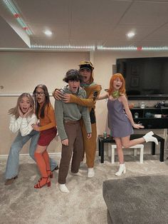 four people are posing in front of a television set with their arms around each other