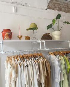 a rack with clothes hanging on it next to a potted plant and other items