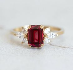 a red and white diamond ring sitting on top of a table