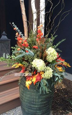 an arrangement of flowers in a large green vase on the ground near some stairs and steps