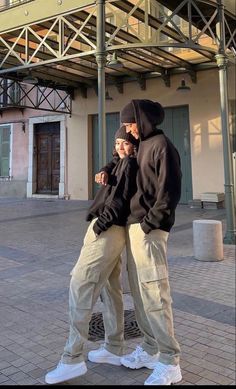 two people standing next to each other in front of a building