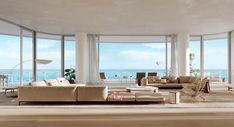 a living room filled with lots of furniture and large windows overlooking the ocean in front of it